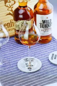 Verre à whisky tulipe vu en gros plan, posé sur table en bois foncé.