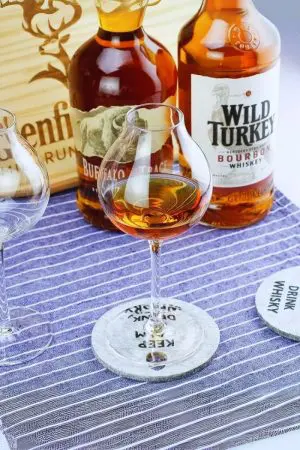 Verre à whisky tulipe vu en gros plan, posé sur table en bois foncé.