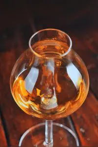 Verre à whisky tulipe posé sur sous-verre en feutre, devant bouteilles de bourbon.