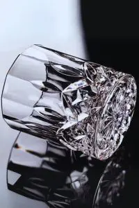 Verre à whisky en cristal sculpté sur une table, capturant l’éclat du spiritueux.