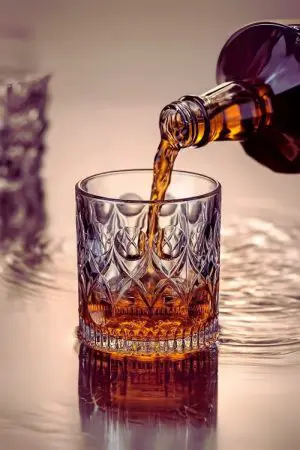 verre à whisky cristal 330 ml en cours de remplissage sur surface réfléchissante