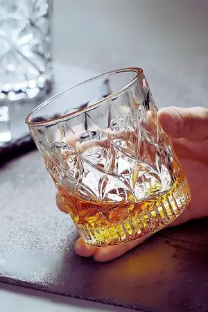 verre à whisky cristal 330 ml tenu en main, partiellement rempli