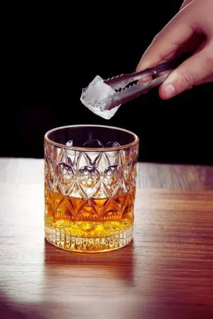 verre à whisky cristal 330 ml posé avec ajout d’un glaçon à la pince