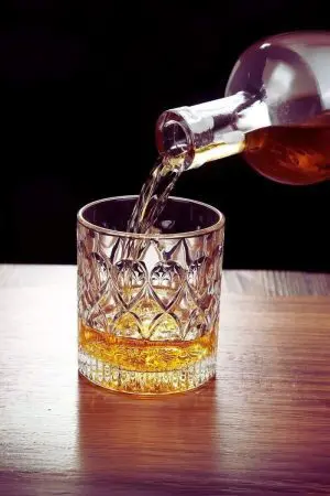 verre à whisky cristal 330 ml en cours de remplissage avec bouteille inclinée