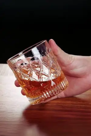 verre à whisky cristal 330 ml tenu en main sur fond noir
