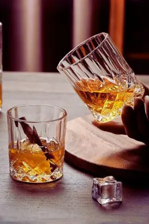 Verres en cristal sculpté remplis de whisky, reflétant un design luxueux et sophistiqué.