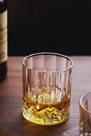 Gros plan sur un verre à whisky en cristal sculpté, révélant sa finition haut de gamme.