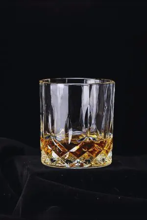 Quatre verres à whisky en cristal sculpté alignés, parfaits pour un apéritif convivial.