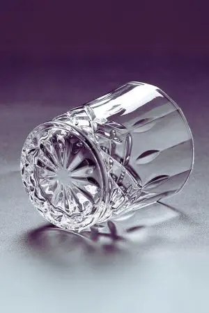 Verre en cristal sculpté incliné, mettant en avant sa forme unique et élégante.