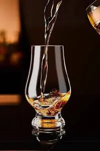 Trois verres Glencairn remplis de whisky sur une table en bois – Expérience de dégustation raffinée