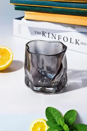 verre à whisky design gris fumé vide posé sur fond blanc avec citron