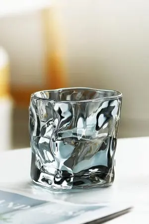 verre à whisky design gris fumé posé sur surface blanche brillante