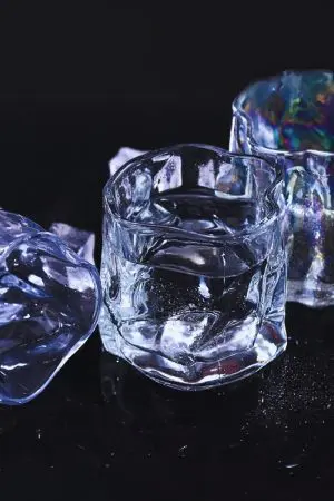 verre à whisky design transparent avec glaçons sur surface noire