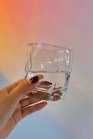 verre à whisky design tenu à la main devant un fond dégradé