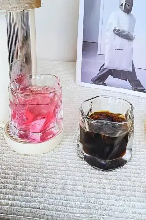 deux verres à whisky design posés sur une table blanche texturée
