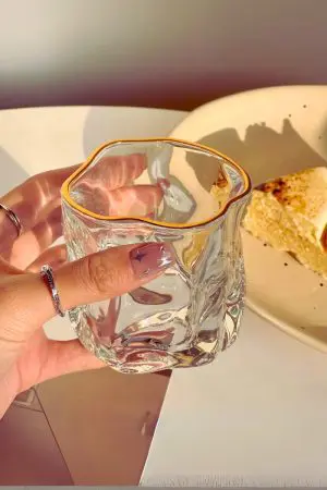 verre à whisky transparent vide tenu à la main avec bord doré