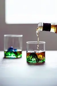 Verre à whisky japonais vert sur table, en cours de remplissage avec bouteille de whisky