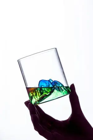 Verre à whisky japonais vert design montagne tenu à bout de doigts