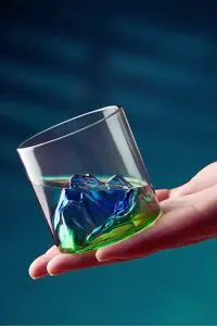 Verre à whisky japonais tenu incliné dans la main, montrant clairement son relief montagneux en détail