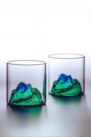 Set de deux verres à whisky montagne vert posés sur une surface sombre