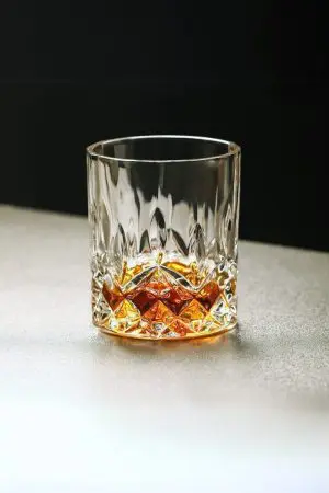 Verre en cristal sculpté rempli de whisky, idéal pour une dégustation raffinée.