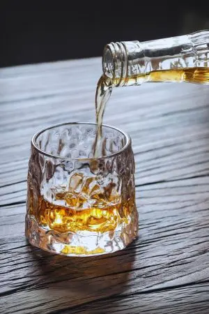 verre à whisky tumbler en cours de remplissage sur table en bois