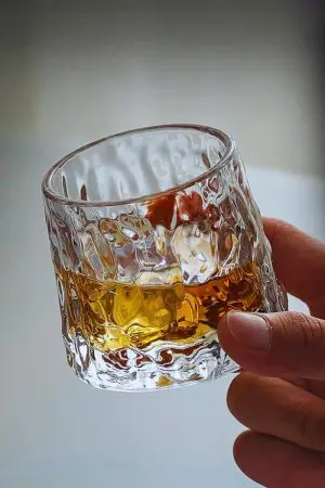 verre à whisky en forme de glaçon tenu à la main