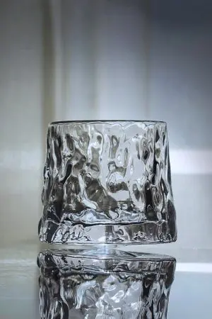 verre à whisky en forme de glaçon posé sur une surface réfléchissante