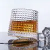 Verre à whisky tumbler incliné sur surface miroir avec liquide ambré