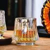 Verre à whisky japonais design colline posé sur table en bois, rempli d'un whisky ambré