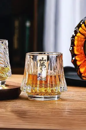 Verre à whisky japonais design colline posé sur table en bois, rempli d'un whisky ambré