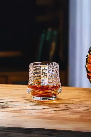Verre à whisky japonais design mer rempli de whisky ambré, tenu en main