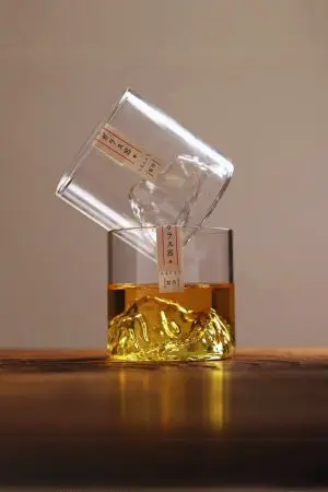 Verre à whisky japonais montagne vide et plein posé sur table avec éclairage naturel