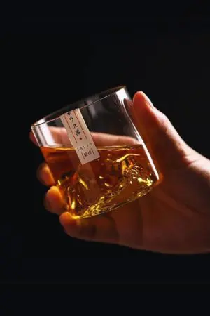 Verre à whisky japonais montagne tenu en main rempli de whisky