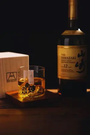 Verre à whisky japonais montagne rempli sur table en bois avec bouteille en arrière-plan