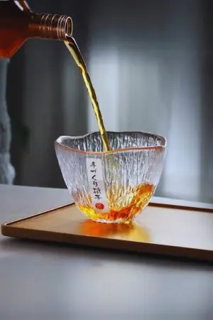 verre à whisky japonais ovale en train d’être rempli sur plateau en bois