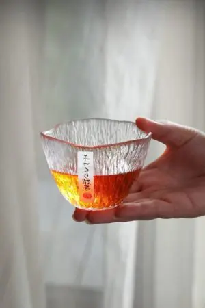 verre à whisky japonais ovale rempli tenu en main avec étiquette japonaise visible