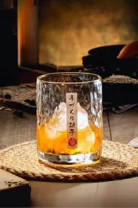 verre à whisky japonais rond en cristal, avec glaçon, posé sur table en bois