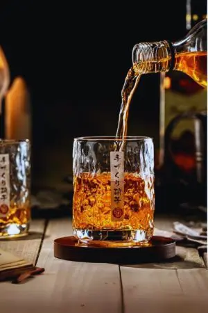 Verre à whisky japonais rond sur socle bois en train d’être rempli