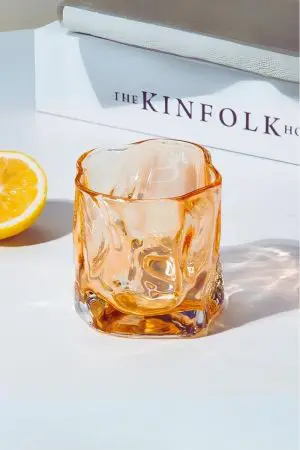 Verre à whisky tumbler ambre vide sur table blanche avec citron.