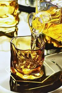 Verre à whisky tumbler ambre en cours de remplissage avec carafe à whisky.