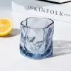 verre à whisky tumbler bleu glacier vide posé sur une table blanche