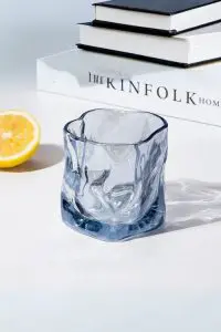 verre à whisky tumbler bleu glacier vide posé sur une table blanche