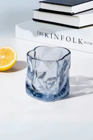verre à whisky tumbler bleu glacier vide posé sur une table blanche