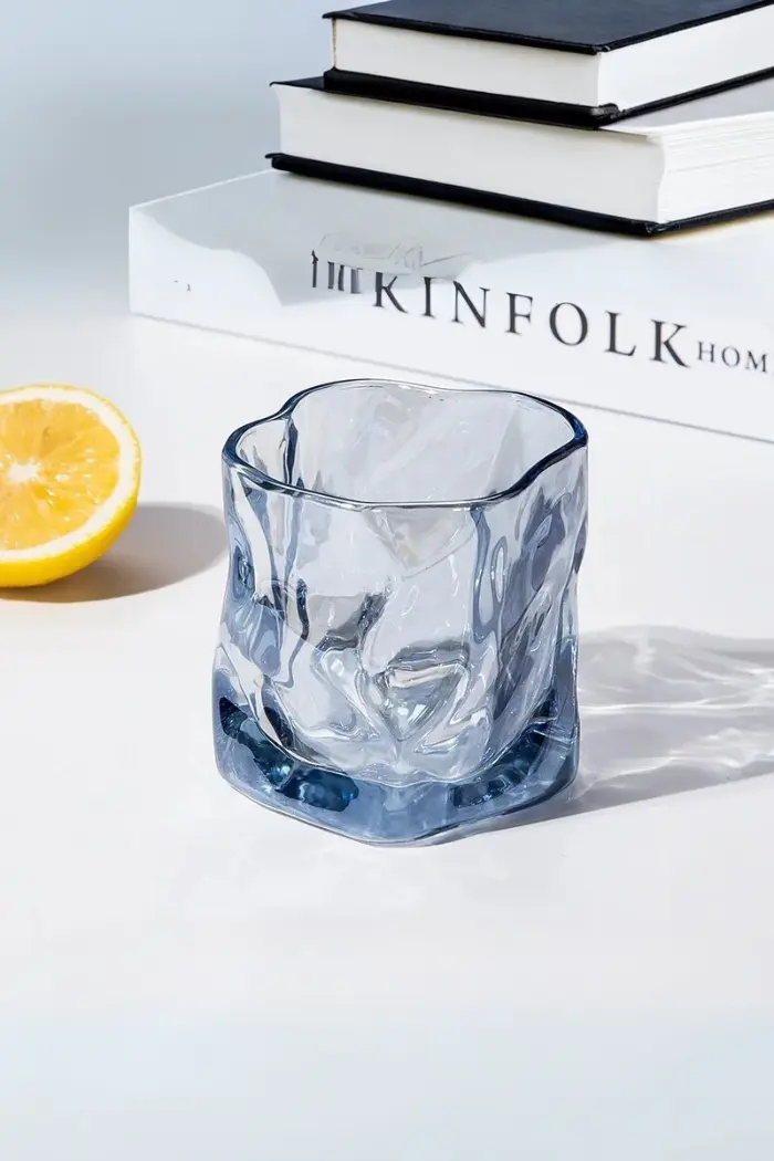 verre à whisky tumbler bleu glacier vide posé sur une table blanche