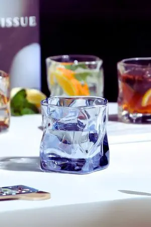 verre à whisky tumbler bleu glacier rempli d’eau sur table blanche