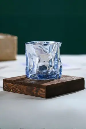 verre à whisky tumbler bleu glacier vide posé sur socle en bois