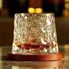verre à whisky tumbler en cristal transparent posé sur un socle en bois, rempli de whisky, sur table marbrée