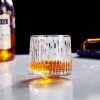 Verre à whisky tumbler texturé rempli, posé directement sur table claire sans sous-verre.