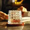 verre à whisky tumbler transparent posé sur un socle en bois sur une table brillante